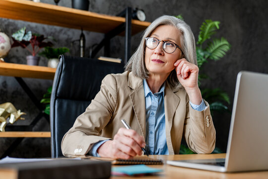 Thinking, business woman or paperwork with laptop for investment strategy, IPS review or planning. Portfolio manager, mature person or happy with tech in office for capital gains or economic research