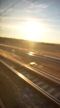 The sun is shining on the train tracks, creating a beautiful and serene scene. The train is moving along the tracks, and the sunlight is reflecting off the train and the tracks