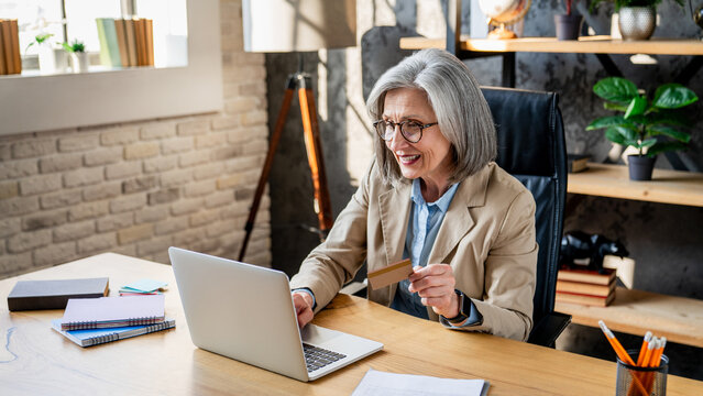 Woman, credit card for payment at desk with laptop for financial info. E-commerce, online banking or shopping and female person in office for company, investment and budget or saving.