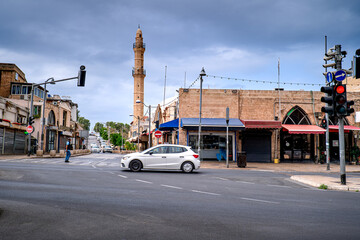 Fototapeta premium Car drives down street in Tel Aviv, mosque in background, Middle East, Israel. Daily life on the city streets.