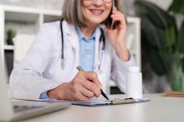 Woman, phone and doctor writing in book for prescription medical history reminder at office. Female...