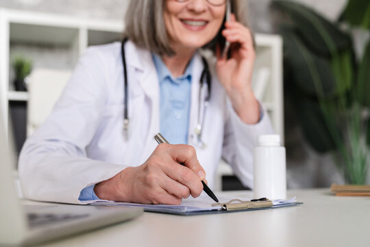 Woman, phone and doctor writing in book for prescription medical history reminder at office. Female person, healthcare worker taking notes with diary for health record or diagnosis at clinic, close up