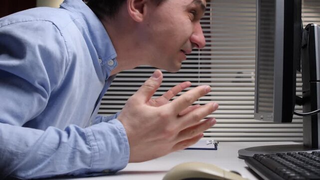 Frustrated man expressing anger and screaming at an old computer monitor, experiencing work related stress, burnout, and emotional breakdown in a dimly lit office setting