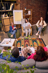 Startup team seated around flip chart in brick loft workspace. Concept of strategy planning...