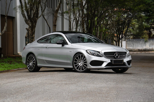 Silver Mercedes-AMG C43 front three quarters view, Luxury car on tree lined road low angle shot