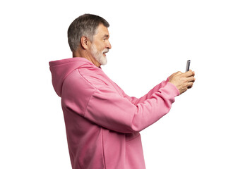 Smiling mature man wearing pink sweatshirt looking at smartphone, isolated on transparent