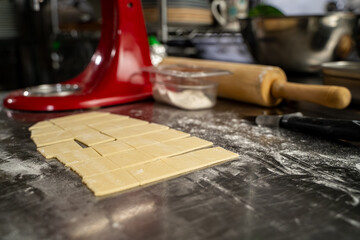 Close up of dough squares on floured stainless steel counter