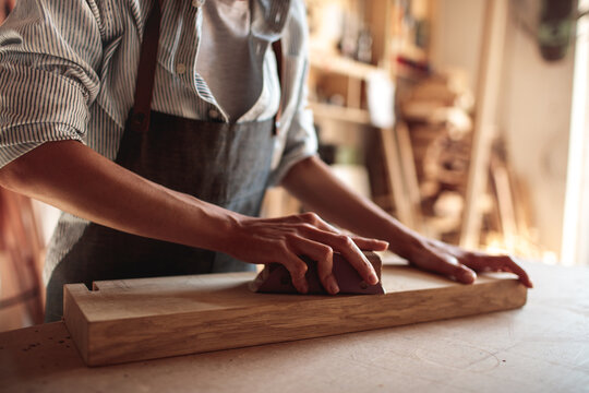 Woodworker sanding wooden board in workshop