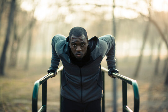 Man performing tricep dips on outdoor park bars