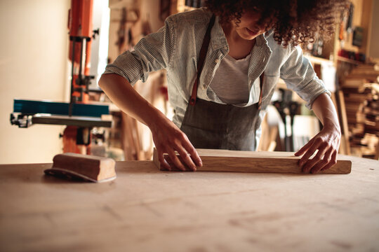 Young artisan sanding wood in workshop
