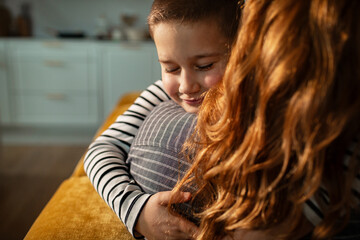 Obraz premium Smiling boy hugging mother at home