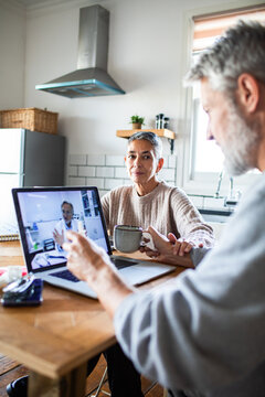 Senior couple on telehealth video call at home kitchen