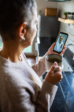 Woman video consulting a doctor in home kitchen