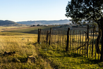 Obraz premium View along a rusticwooden fence over a valley in rural landscape of Eswatini.