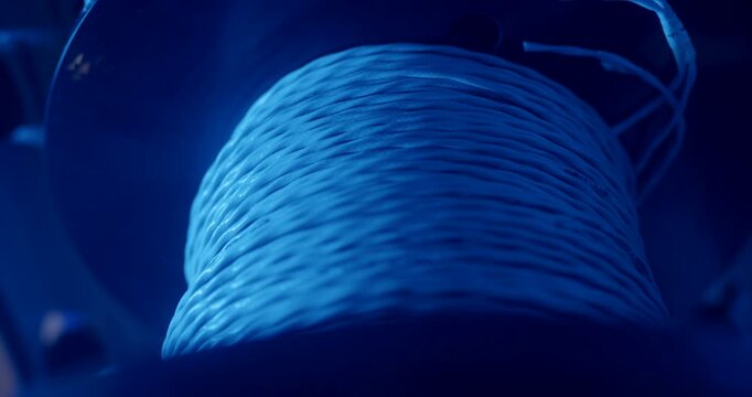Close up of industrial cable spool with white wire under blue light