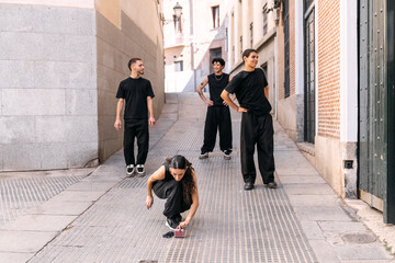 Young diverse street dancers getting ready on a city street, setting up music for their hip hop routine