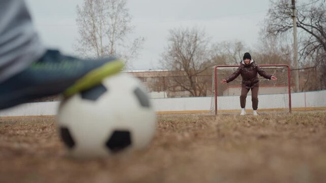 attacker dashes past goalkeeper, closeup of muddy pitch during intense soccer practice session, dynamic scene showing ballplayer evading goalkeeper on muddy playing field with energetic footwork