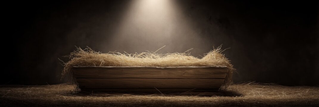 Wooden manger with straw under soft spot light. Empty wooden manger with straw receiving warm light, symbolizing birth and new beginnings
