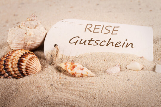 Reisegutschein - Tafel im Sand mit Muscheln