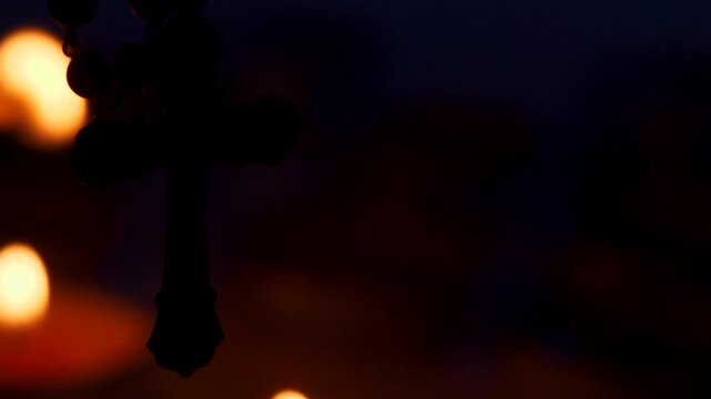 Close up footage of old Catholic crucifix with candles being lit on softly blurred background. scene conveys calm and reverent atmosphere, symbolizing faith, prayer and spiritual devotion