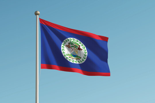 Belize national flag waving on pole against clear blue sky background.