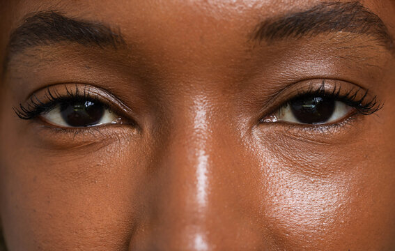 Central facial region is showing both eyes and nose bridge in studio, with mascara and catchlights