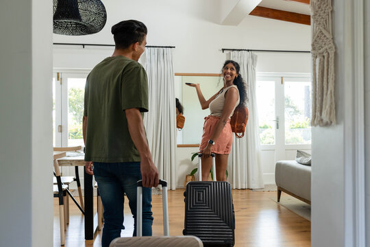 Two hard-shell suitcases are sitting near glass doors in bright rental entry, plant visible