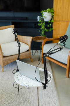 Small terrazzo table is hosting open silver laptop and microphone booms in home studio