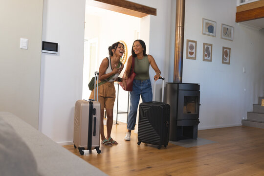 Two hard-shell suitcases are standing near bright doorway in modern living area with wood stove