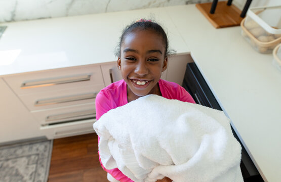 Large stack of white towels is sitting on white quartz countertop in modern home kitchen