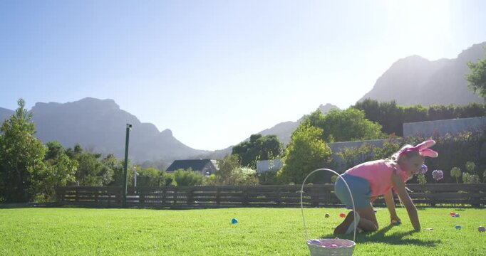 Female child hearing start, crawling, placing eggs into basket on lawn with bunny ears, copy space