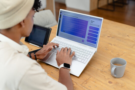 White laptop showing blue chat interface is resting on wooden table with coffee mug and tablet