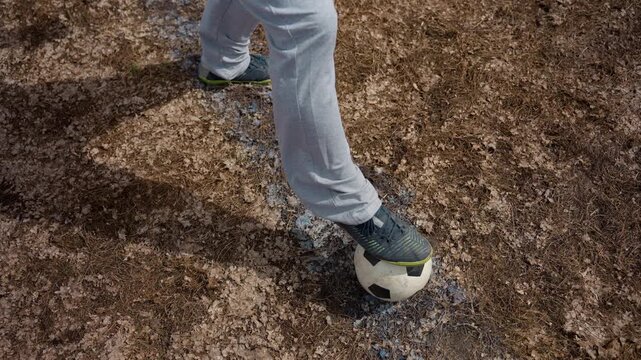 sole trapping ball on marked ground, precise contact and balance in slow rhythm; close aerial to foot interaction, muddy pitch textures and focused training vibe for coaching and technique tutorials