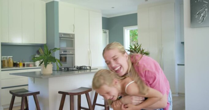 Mother and child coming from behind, hugging and lifting gently at kitchen island, bonding