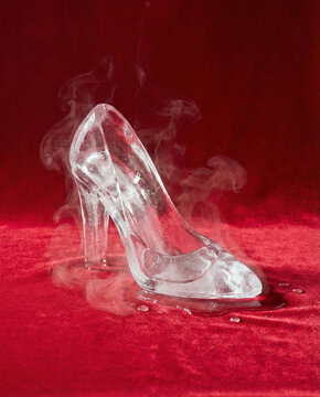 Magical glass or Ice slipper sandel with mystical smoke and dew drops on a rich red background.