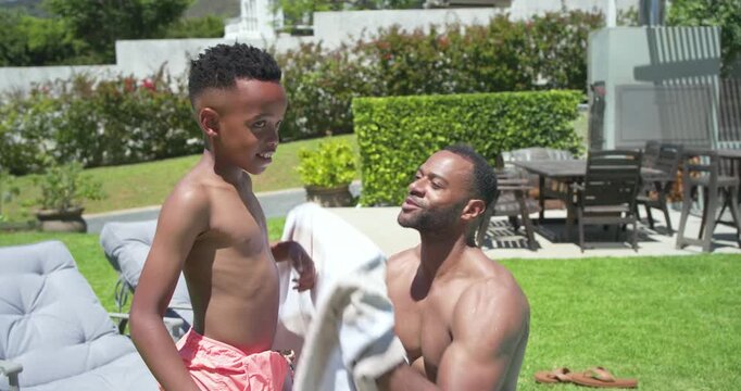 African American dad and son poolside post-swim dad adjusting trunks patting wrapping towel to dry