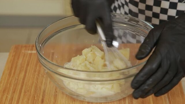Professional chef mashing baked celery root while making puree