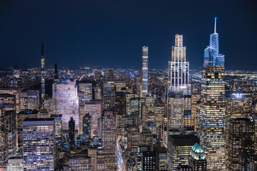 Night aerial view of Midtown Manhattan skyline with modern illuminated skyscrapers and dense city lights in New York City USA