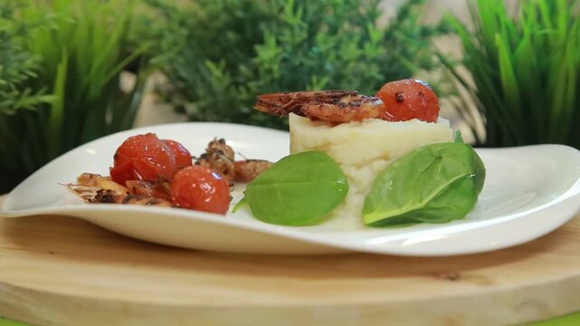 Plating and presentation of celery root puree with fried shrimp and cherry tomatoes