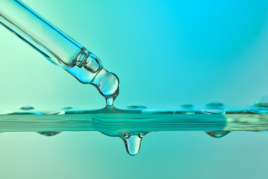 Pipette dripping liquid drop into green water surface