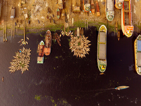 Aerial view of boats and ships of varying sizes docked near the shore, creating a mosaic of colors and textures against the dark water, Dhaka, Dhaka Division, Bangladesh.