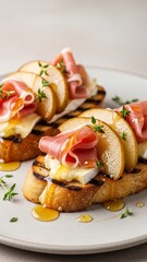 Grilled sourdough toasts topped with ham, brie, pear and thyme with honey glaze for upscale appetizer photography and menu use
