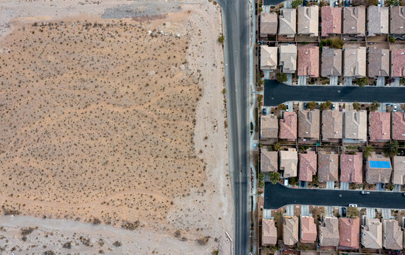 Aerial view of the sharp contrast between arid land and densely packed residential homes divided by a long street, Hopewell Township, New Jersey, United States.