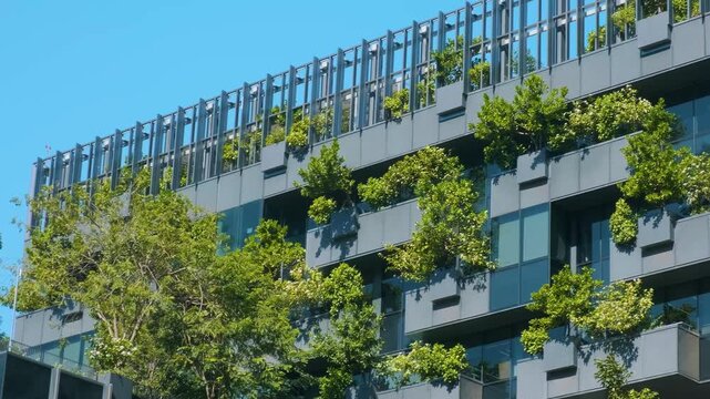 Modern eco-friendly building with vertical garden and trees on balconies in urban environment in Bangkok city, Thailand. Green architecture, sustainable design, eco city