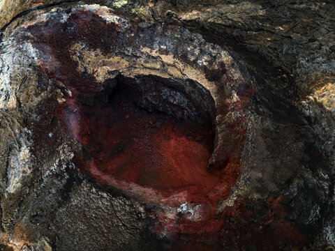 Aerial view of a dark cave with a red mineral deposit, Iceland.