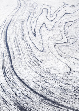Aerial view of swirling, sinuous patterns etched into the ice, a mesmerizing dance of light and shadow creating ethereal beauty, Iceland.