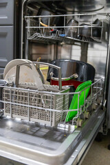 Dirty dish in open integrated dishwasher. Open dishwasher with dirty dishes inside before washing. full loaded dishwasher ready for washing.