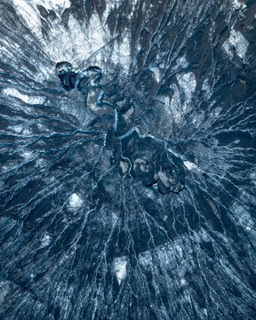 Aerial view of icy fractal patterns sprawling across a glacial landscape, where sapphire fissures carve through the frozen expanse, Reykjavik, Iceland.