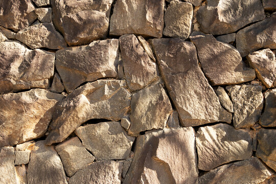 A straight-on close-up reveals a rustic stone wall texture. 