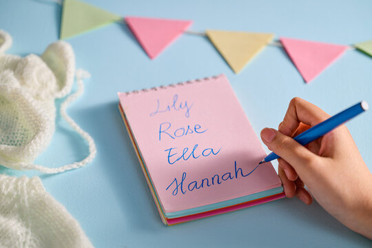 Baby names written in a notebook with a pen